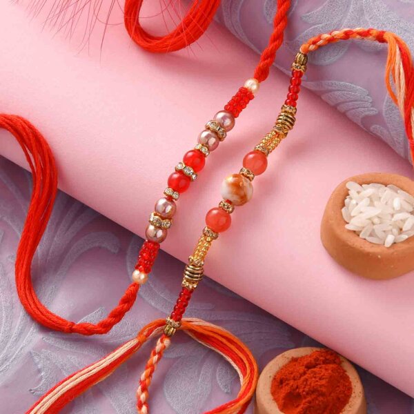 Set of two rakhi with red and orange round beads ,Pista roll and Thali